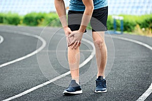 Man in sportswear suffering from knee pain at stadium