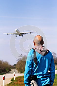 Man is looking at the plane which is landing