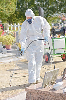 Man spraying chemical weed killer in cemetery