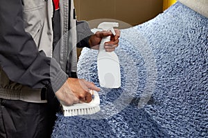 Man Spraying Detergent On Grey Carpet To Remove Stain in professional cleaning service