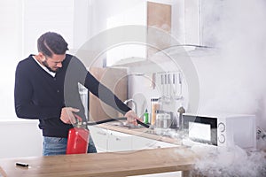 Man Spraying Fire Extinguisher On Microwave Oven