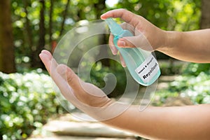 A man spraying insect and mosquito repellent to his hand in the outdoor