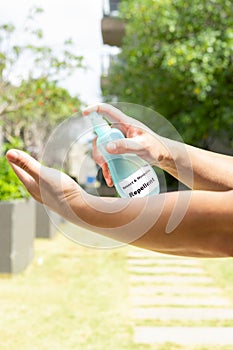 A man spraying insect and mosquito repellent to his hand in the outdoor at vertical composition