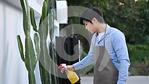 A man spraying insecticide from a spray bottle to cactus.