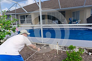 Man spraying roundup around Florida pool