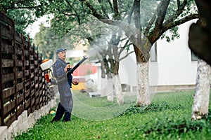 Man spraying toxic pesticides and herbicides in fruit orchard