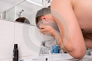 Man spraying water on his face in the bathroom