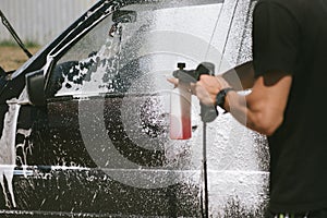 A man sprays a cleaning agent washing a high pressure on the car