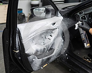 A man sprays cleaning foam on the interior of a car.