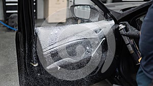 A man sprays cleaning foam on the interior of a car. photo