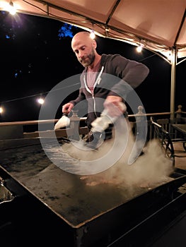 Man sprays hot grill with water to steam clean