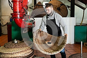 Man spreading milled olives on fiber disks to press