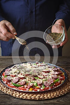 Man sprinkle with spice pizza from a glass sauser