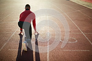 Man sprinters at starting position ready for race on racetrack