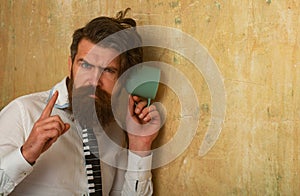 Man spying, eavesdropping. Secret and spy concept. Man eavesdrops using mug near wall. Guy secretly listen conversation photo