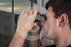 Man is spying his neighbours with binoculars
