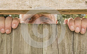 Man spying through a wooden fence in the garden