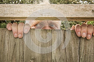 Man spying through a wooden fence in the garden