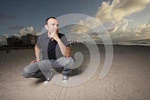Man squatting on the beach