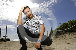 Man squatting on the sand with hand on head