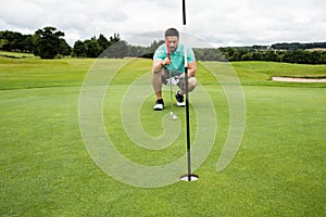 Man squatting to line up his putt