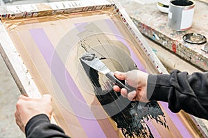 Man squeegeeing silkscreen in a workshop. Serigraphy photo