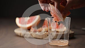 man squeeze grapefruit into tumbler glass on wood table