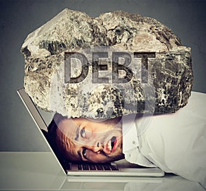 Man squeezed between laptop and rock. Student loan debt concept