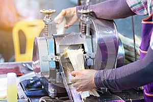 Man squeezes a sugar cane to make fresh, organic juice with a hand powered juicer. Healthy product