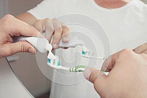 Man squeezes toothpaste on the toothbrush