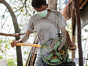 The man is squeezing juice from sugar cane. Using manual Mechanism for that