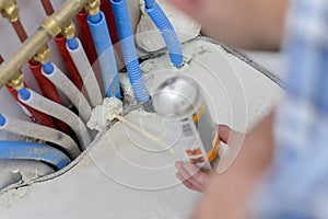 Man squirting expanding foam around pipes