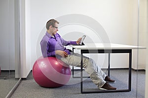 man on stability ball at desk