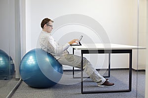 man on stability ball at desk