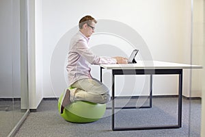 Man on stability ball working with tablet