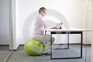 Man on stability ball working with tablet