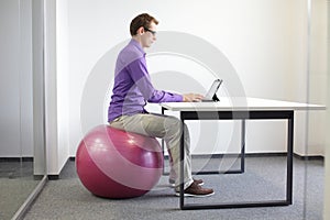 Man on stability ball working with tablet