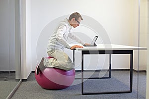 Man on stability ball working with tablet