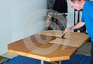 Man Staining A Tabletop