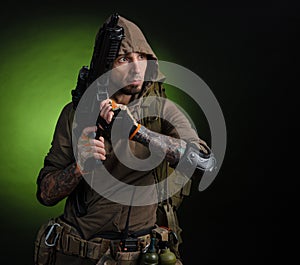 Man Stalker with a gun with an optical sight and a backpack on a dark background