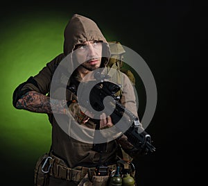 Man Stalker with a gun with an optical sight and a backpack on a dark background