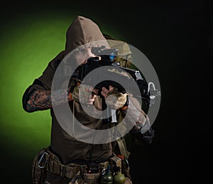 Man Stalker with a gun with an optical sight and a backpack on a dark background