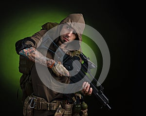 Man Stalker with a gun with an optical sight and a backpack on a dark background