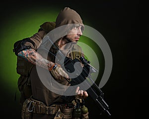 Man Stalker with a gun with an optical sight and a backpack on a dark background