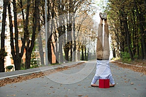 Man stand on head on park road. Student with book upside down in autumn outdoor. Work life balance. Education and