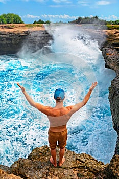 Man stand on high cliff and look at breaking waves