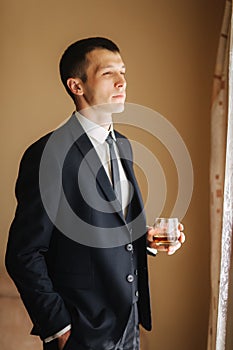 Man stand from side to window and drind a wiskey