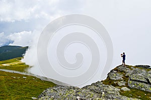 The man stand on top surrounded by fog and low clouds near Transalpina road in Romania