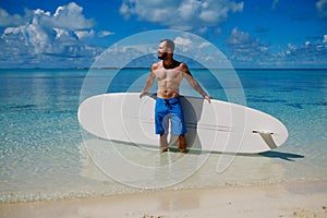 Man with Stand Up Paddle Board on the beach in Bahamas