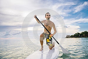 Man stand up on paddle board at sunset